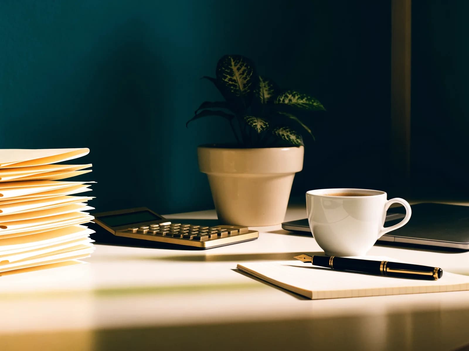 An orderly desk with client tax files, a calculator and a laptop